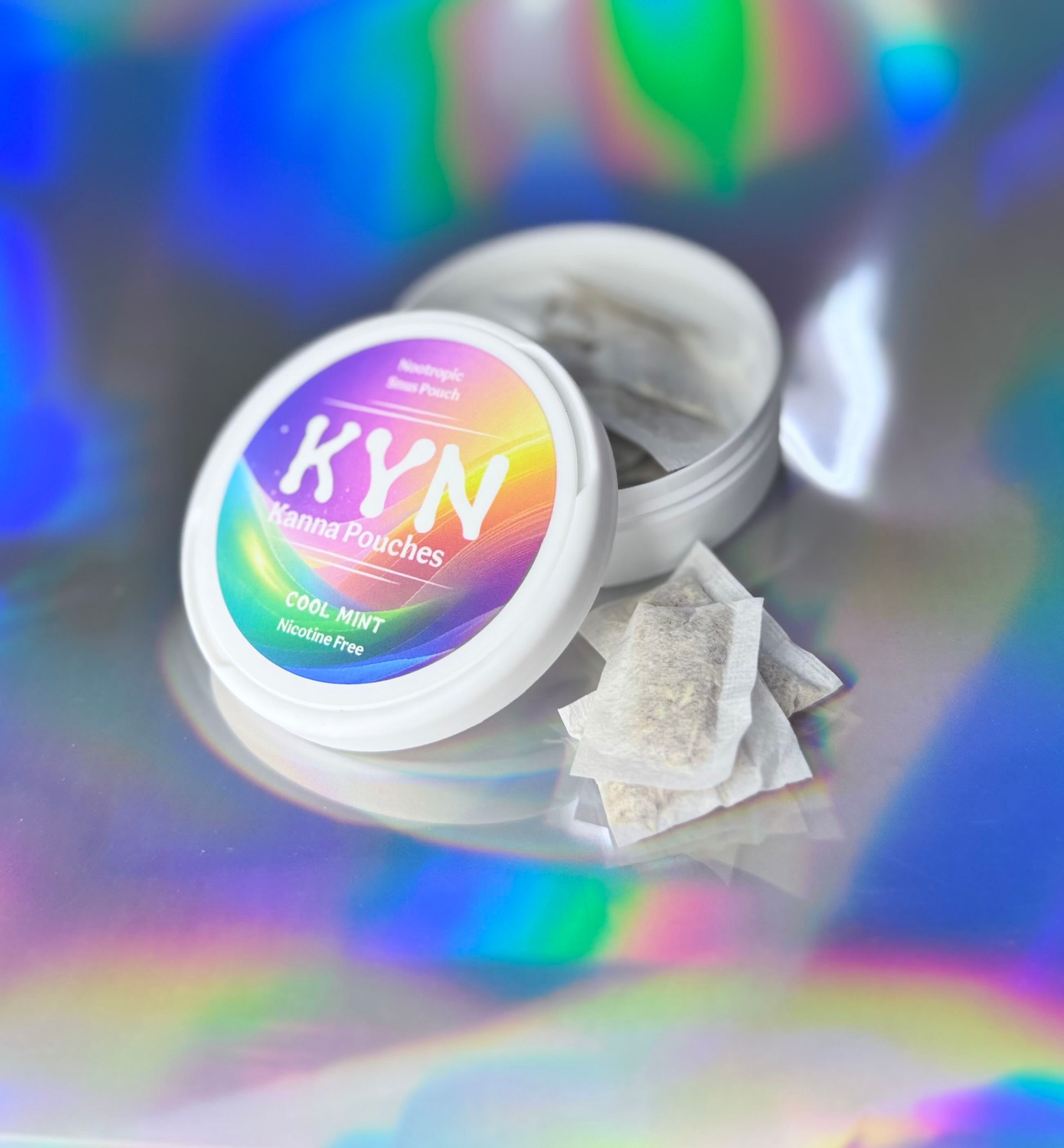 Open white container of “KYN Kanna Pouches – Cool Mint,” showing individual nicotine-free nootropic pouches beside the lid on an iridescent, rainbow-reflective background.