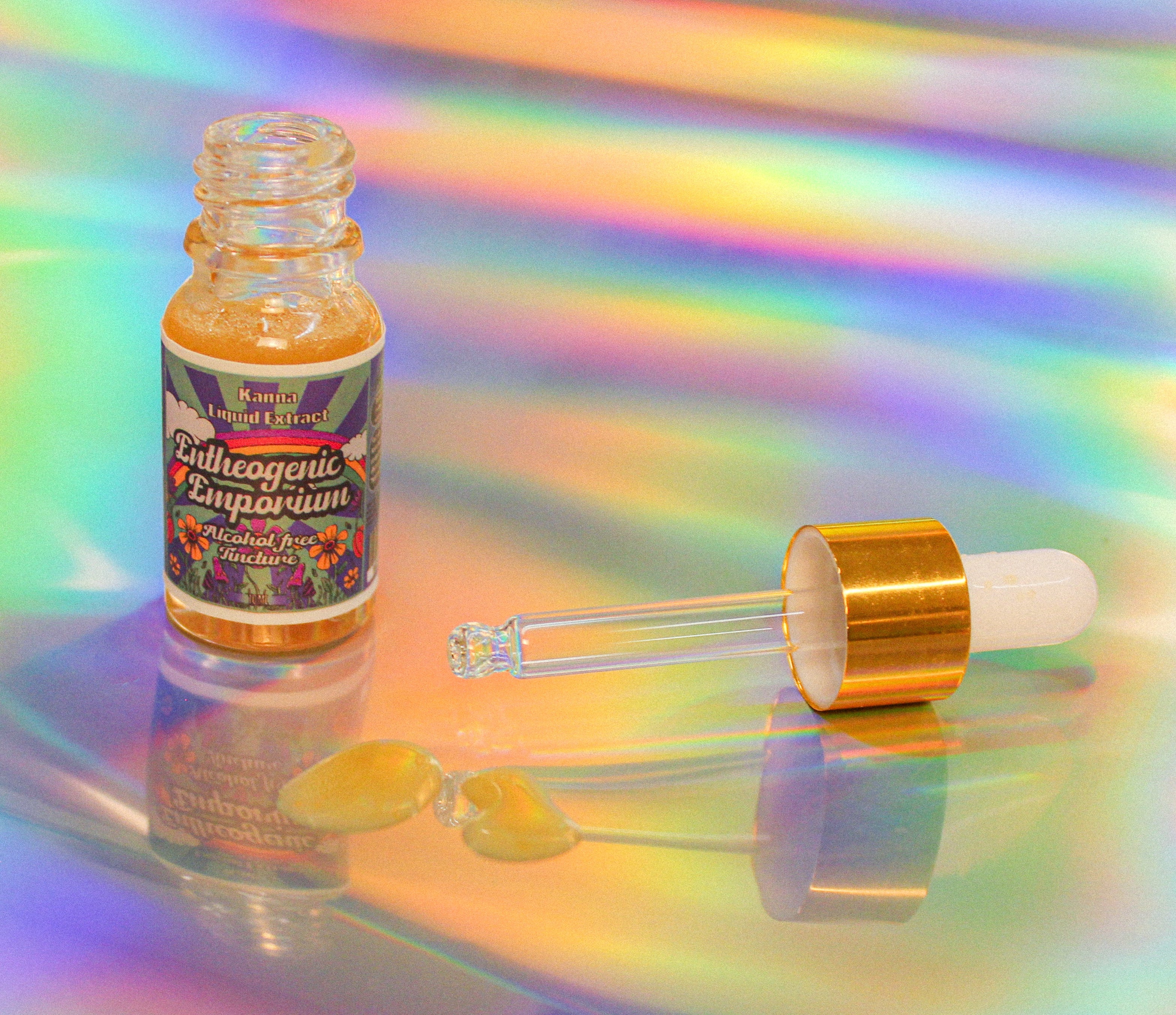 Kanna liquid extract tincture in a clear glass dropper bottle with gold cap, featuring amber-colored herbal extract, displayed on a soft iridescent holographic background with a visible drop of liquid.