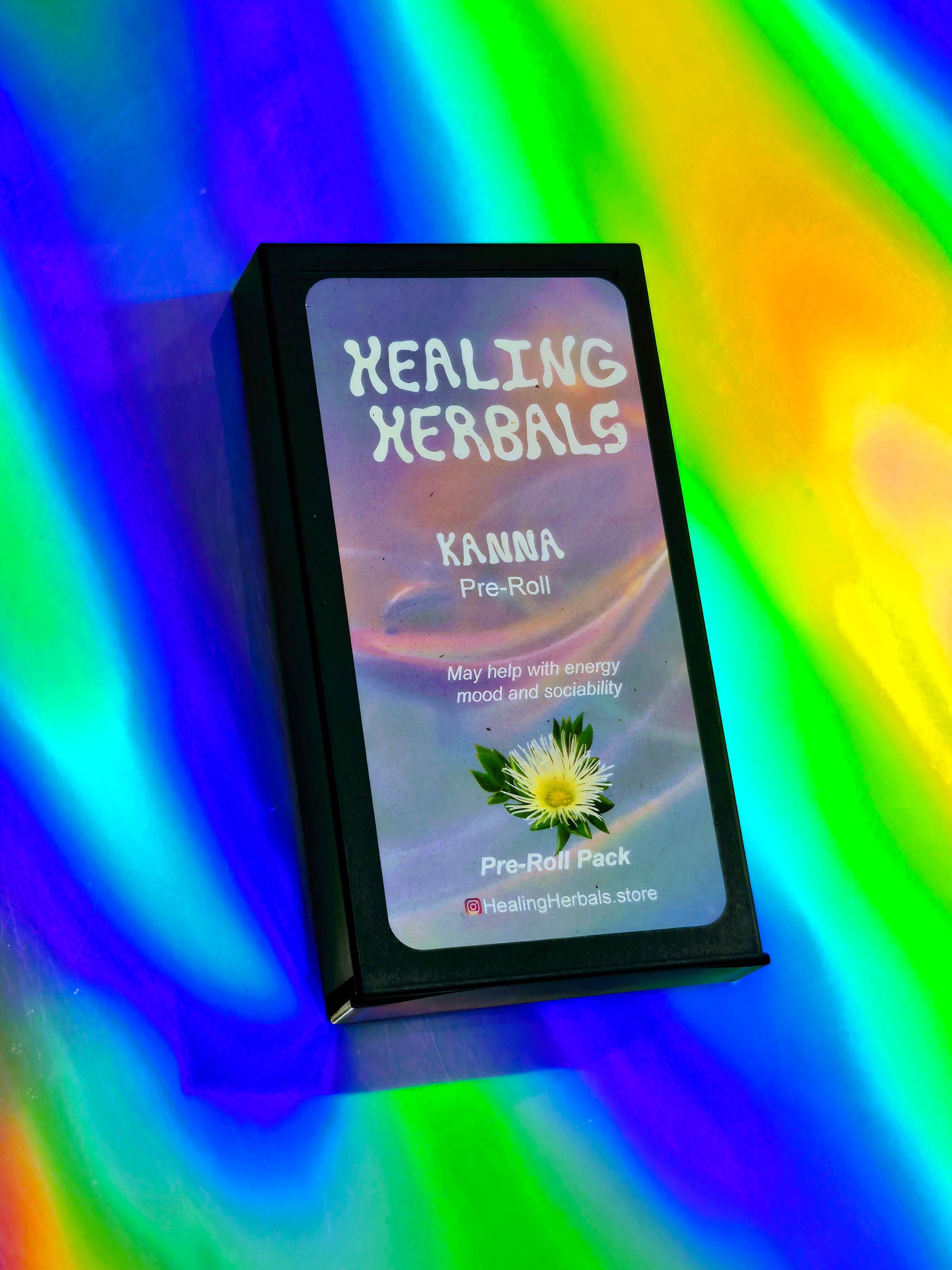 Healing Herbals Kanna pre-roll pack shown closed in a sleek black case, featuring branded label with kanna flower illustration, photographed on a vibrant iridescent rainbow background.