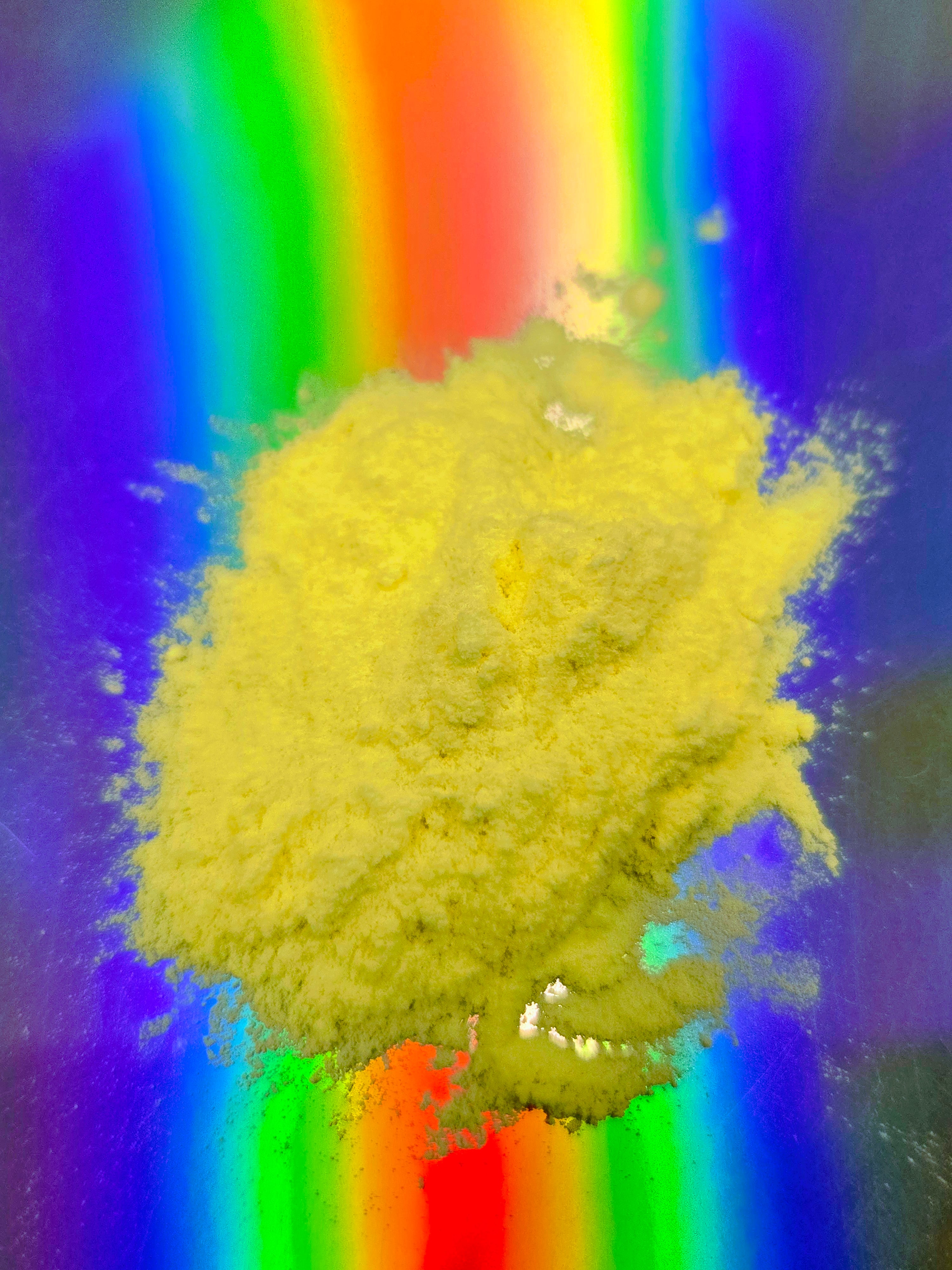 Close-up top-down image of fine yellow Kava extract powder by Healing Herbals, showcasing a smooth, fluffy texture displayed on a vibrant holographic rainbow background.