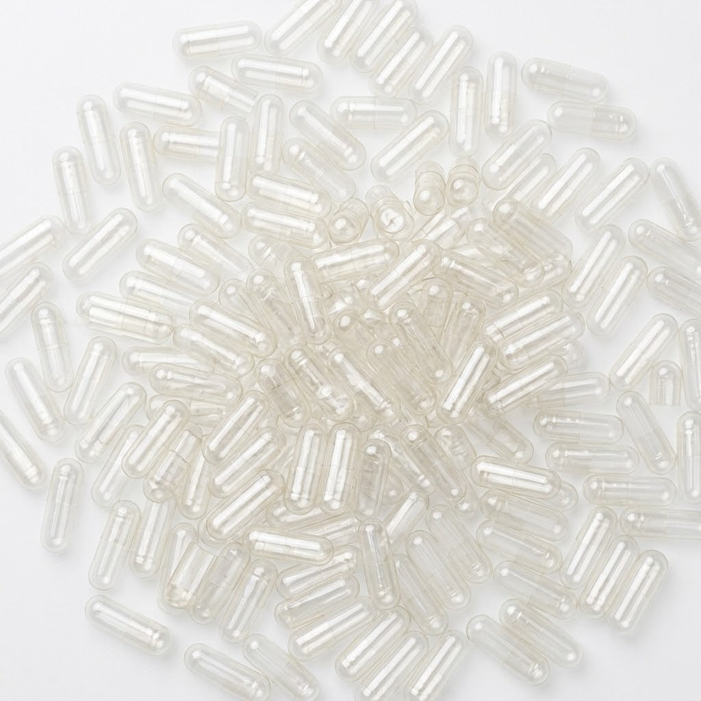Loose pile of empty clear two-piece vegan capsules, size 00, on a white background