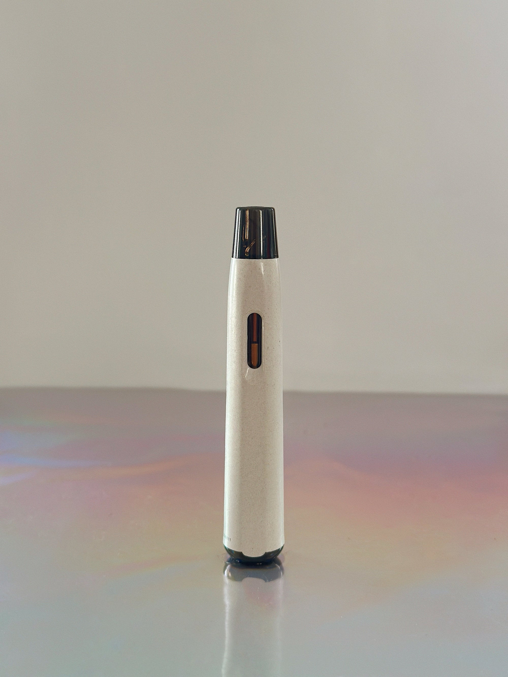 Blue Lotus Vape Pen is a white thin long vaporizer pen filled with a blue lotus extract over a grey background with slight psychedelic colors over the grey