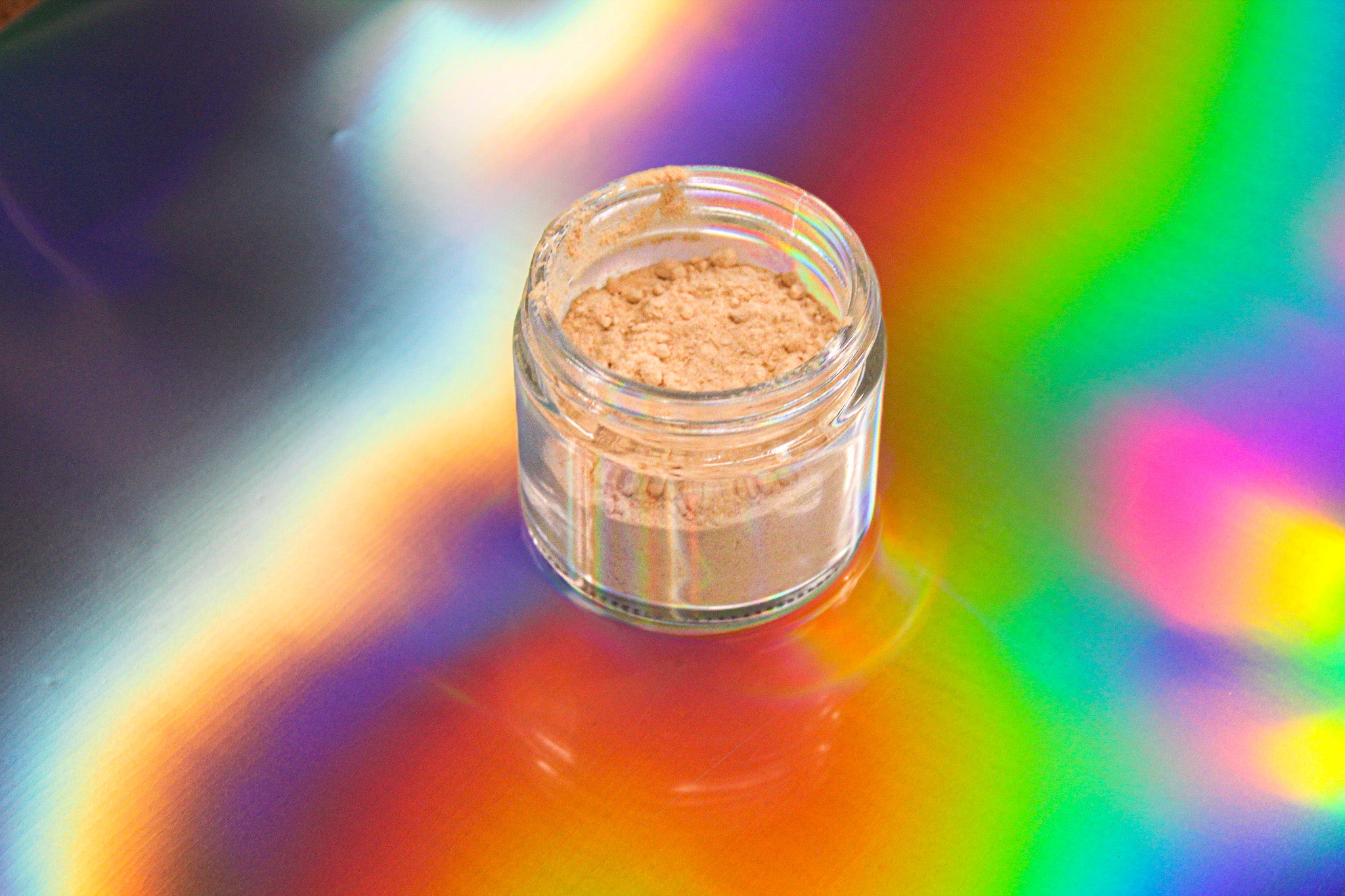 FS-33 kanna extract high mesembrenone powder by Healing Herbals in a small clear glass jar, featuring fine tan powder set against a vibrant iridescent rainbow background.