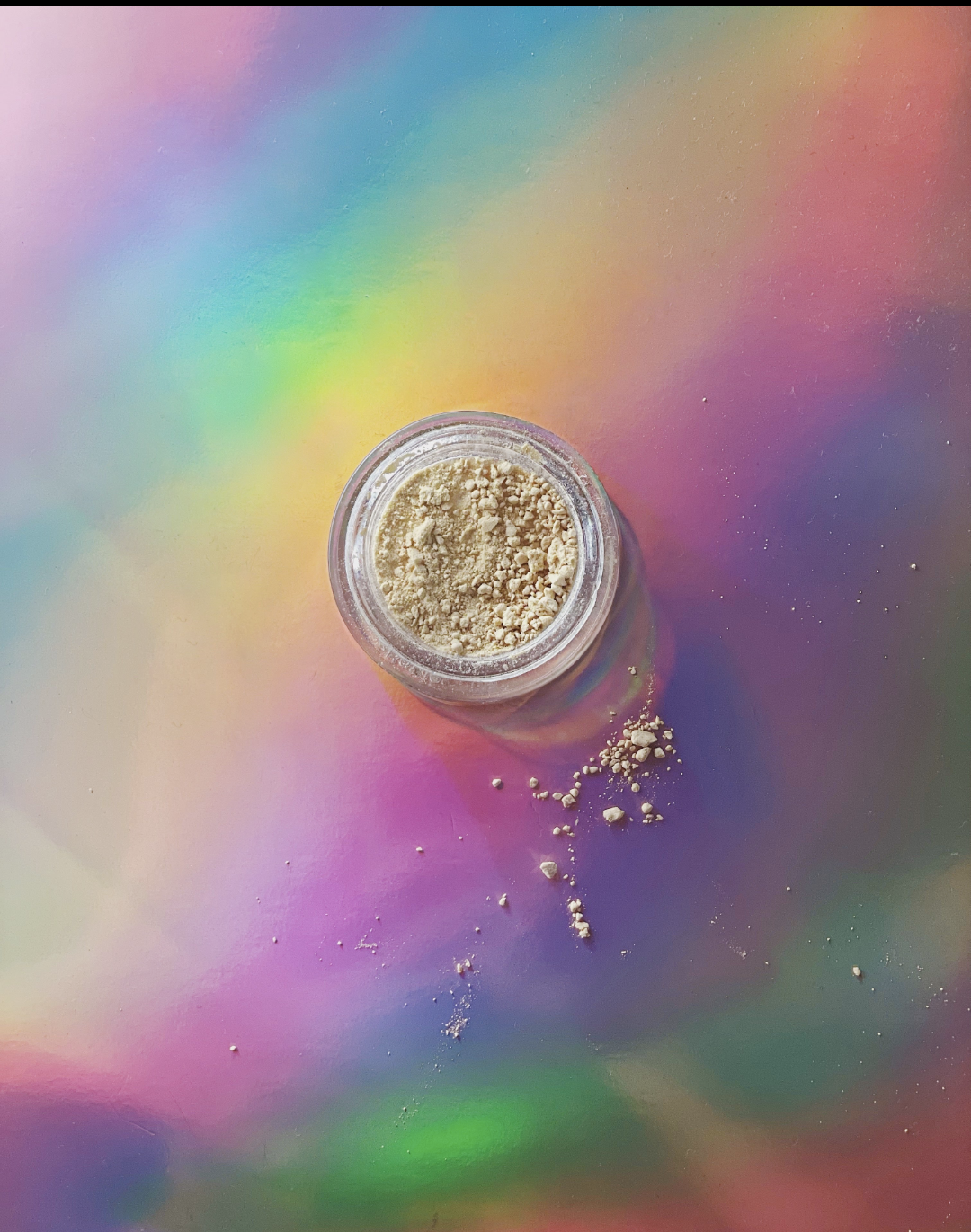 Open glass jar containing 15% active alkaloids kanna extract powder, with light beige granules lightly scattered on a soft rainbow gradient background.