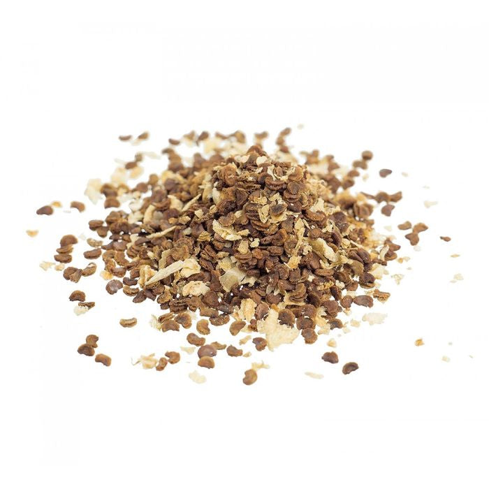 Close-up of dried kanna seeds (Sceletium tortuosum) scattered in a small pile on a clean white background, showing natural brown and tan seed fragments.