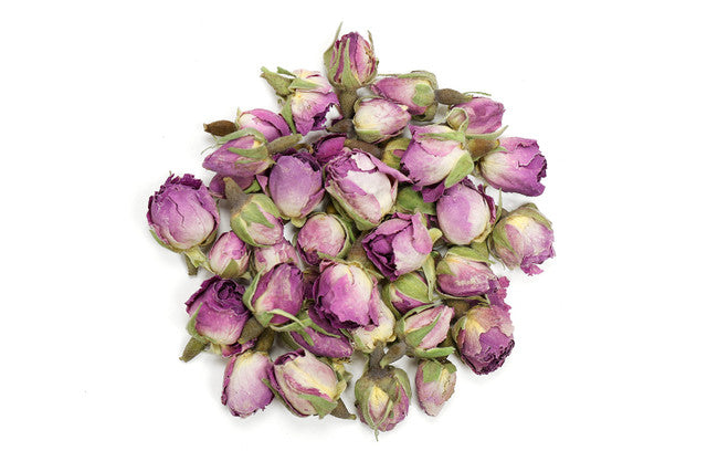 View of whole dried rose buds with pink and purple petals and green sepals, loose herbal botanicals on a clean white background.